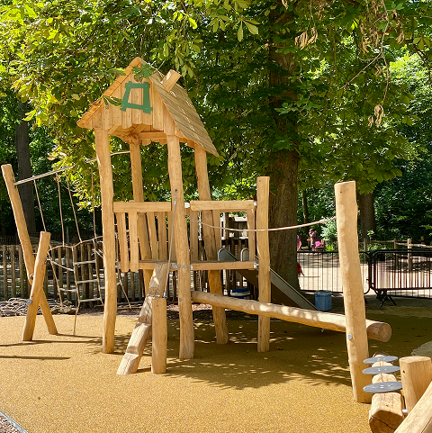 Low-carbon wooden playground beneath leafy trees